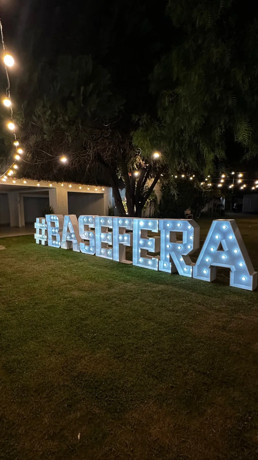 Letreiro iluminado BASE FERA em um encontro noturno ao ar livre